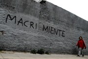 A woman walks past a wall spray painted with a message that reads in Spanish “Macri lies”, Buenos Aires, Argentina, Aug. 30, 2018 (AP photo by Natacha Pisarenko).