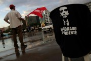 A supporter of presidential candidate Fernando Haddad waves a banner near a vendor selling shirts featuring the eventual winner, Jair Bolsonaro, Brasilia, Brazil, Oct. 26, 2018 (AP photo Eraldo Peres).