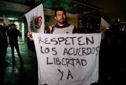 A supporter of former FARC rebel Jesus Santrich holds a sign that reads in Spanish “Respect the freedom agreements” during a protest against his arrest in Bogota, Colombia, April, 9, 2018 (AP photo by Fernando Vergara).