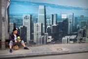 A worker sits in front of a billboard at a construction site in Beijing, China, May 16, 2019 (AP photo by Mark Schiefelbein).