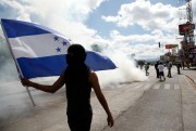 A demonstrator waves a Honduran flag during a protest against the government of President Juan Orlando Hernandez in Tegucigalpa, Honduras, Jan. 27, 2019 (AP photo by Fernando Antonio).