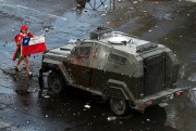 A protester faces off with an armored police vehicle during an anti-government march in Santiago, Chile, Oct. 22, 2019 (AP photo by Esteban Felix).