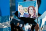 A supporter of Cristina Fernandez and her late husband Nestor Kirchner holds up a flag featuring their portraits during a campaign rally for the leading opposition ticket, in Santa Rosa, Argentina, Oct. 17, 2019. (AP photo by Natacha Pisarenko).