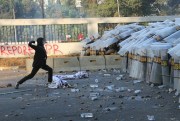 A student protester throws a rock at riot police during a clash in Jakarta, Indonesia, Sept. 30, 2019 (AP photo by Tatan Syuflana).