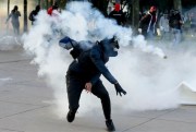 A student throws a tear gas canister back at police during clashes at the National University in Bogota, Colombia, Nov. 26, 2019 (AP photo by Ivan Valencia).