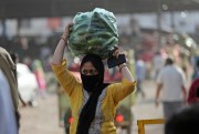 A woman carries vegetables outside a wholesale market in Jammu, India, May 2, 2020 (AP photo by Channi Anand).