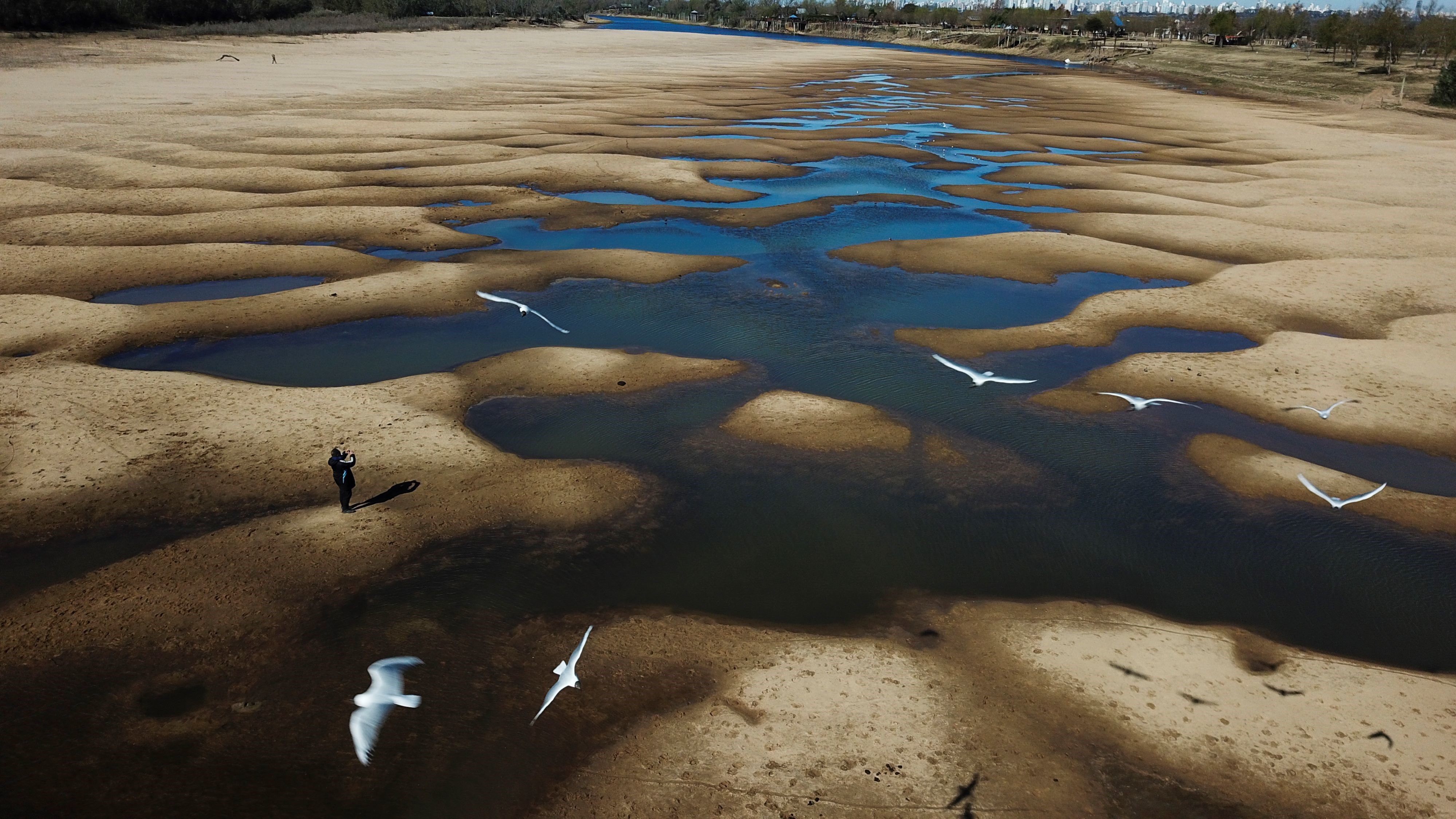 A man takes photos of the exposed riverbed of the Old Parana River