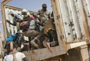 Migrants climb into a truck to head north into Algeria.