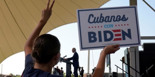 A woman holds up a sign that reads "Cubans with Biden."