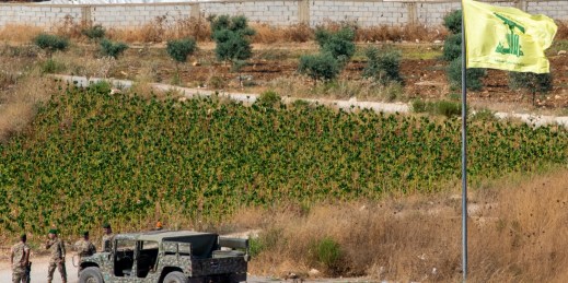 Lebanese soldiers next to a Hezbollah flag patrol.