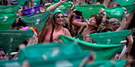 Women hold up green bandanas, a symbol of abortion rights in Latin America.