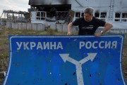 Ukrainian historian Yuri Savchuk carries a road sign pointing to Ukraine and Russia.