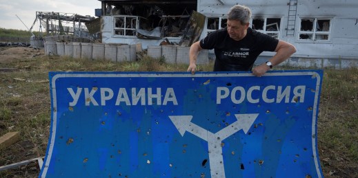 Ukrainian historian Yuri Savchuk carries a road sign pointing to Ukraine and Russia.