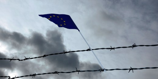 A European Union flag hangs from barbed wire.