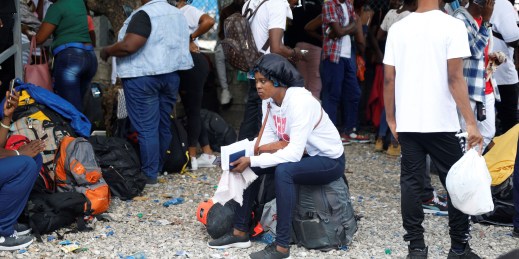 People wait at Toussaint Louverture International Airport after the Haitian government banned all charter flights to Nicaragua.