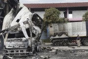 A Thai officer stands beside a burnt oil tanker in southern Thailand.