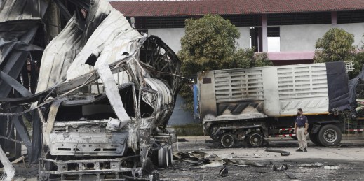 A Thai officer stands beside a burnt oil tanker in southern Thailand.