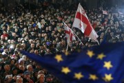 Protesters wave Georgia’s national flag and an EU flag.