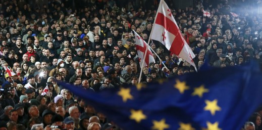 Protesters wave Georgia’s national flag and an EU flag.