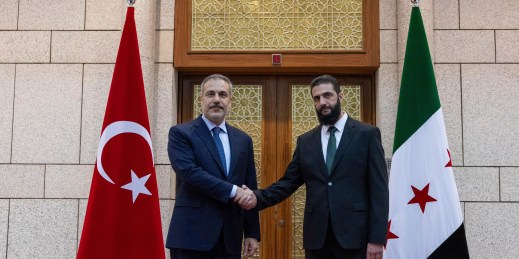 Turkish Foreign Minister Hakan Fidan shakes hands with Ahmad al-Sharaa.