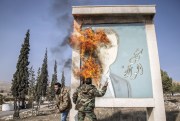 A man burns a picture of former Syrian President Bashar al-Assad.