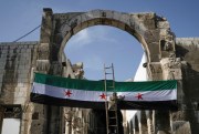 A worker sets up a Syrian revolutionary flag at the entrance of the Umayyad Mosque.