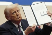 U.S. President Donald Trump holds up an executive order.