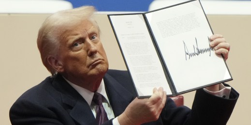 U.S. President Donald Trump holds up an executive order.